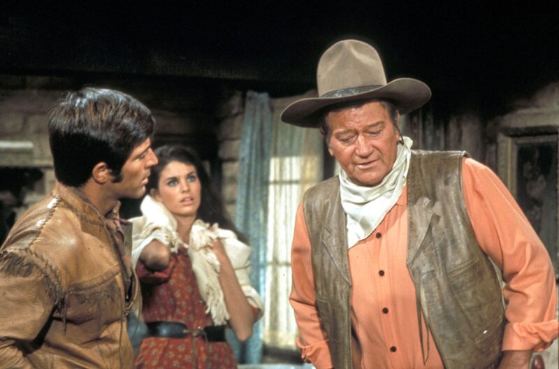 Nach seinem Arztbesuch kehrt McNally (John Wayne, re.) zurück zu Amelita (Sherry Lansing, Mi.), Cordona (Jorge Rivero, li.) und Shasta. – Bild: SWR/​Telepool