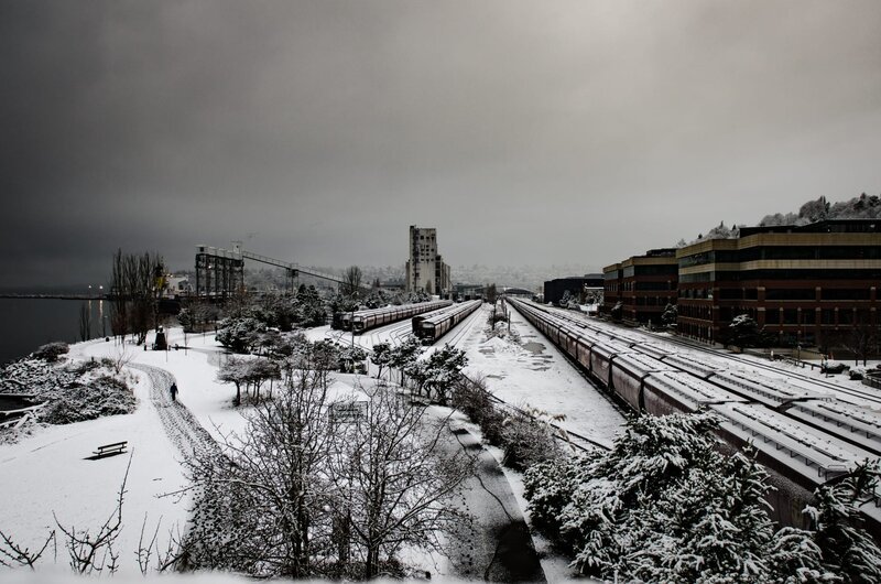 Long lines of snow covered train cars wait to be moved following a surprise snow storm. A lone walker follows the trail through Myrtle Edwards Park in Seattle. – Bild: Discovery Communications