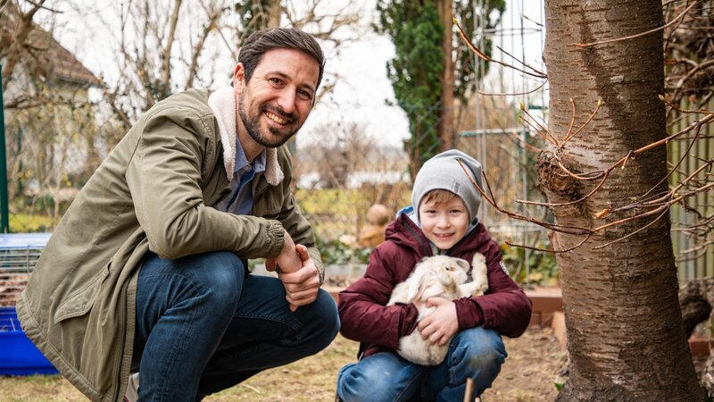 Matthias Luginger gemeinsam mit dem geflüchteten Jungen Ilia im Garten der Gastfamilie. – Bild: BR/​Maximus Film GmbH