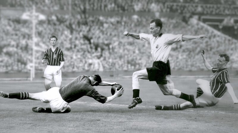 Bei diesem spektakulären Einsatz im Pokalfinale 1956 bricht sich Bert Trautmann das Genick. Trotz der schweren Verletzung beendet er das Spiel für seine Mannschaft – Manchester City. – Bild: Radio Bremen /​ Getty Images