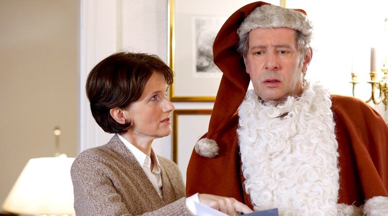 Dirk Matthies (Jan Fedder, r.) muss den betrunkenen Weihnachtsmann vertreten. Fiona Marwitz (Victoria Trauttmannsdorff, l.) gibt ihm Tipps, wie er die Kinder beschenken soll. – Bild: NDR/ARD/Sandra Hoever Dirk Matthies (Jan Fedder, r.) muss den betrunkenen Weihnachtsmann vertreten. Fiona Marwitz (Victoria Trauttmannsdorff, l.) gibt ihm Tipps, wie er die Kinder beschenken soll. – Bild: NDR/ARD/Sandra Hoever