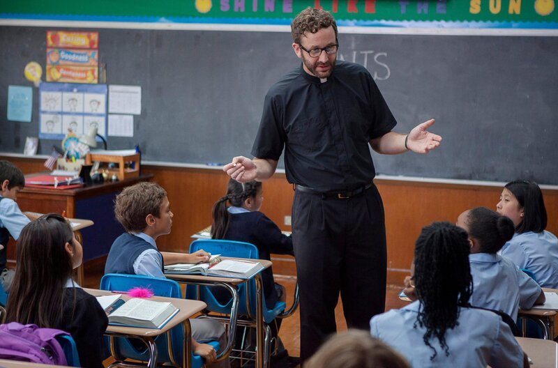 Olivers Lehrer (Chris O’Dowd, Mitte) stellt eine ungewöhnliche Schulaufgabe: Die Kindern sollen „ihre“ Heiligen“ finden. – Bild: ZDF und ARD Degeto/​Splendid Film.