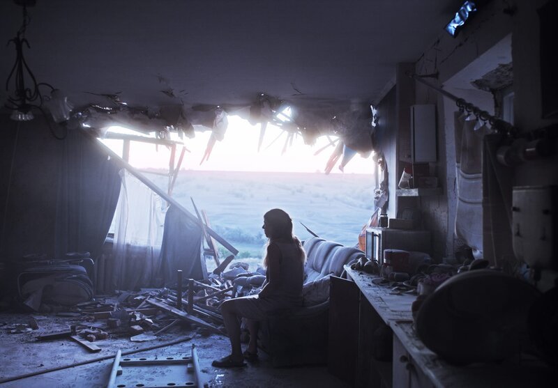 Die hochschwangere Irka (Oxana Cherkashyna) sitzt niedergeschlagen in ihrem zerstörten Wohnzimmer, nachdem eine fehlgeleitete Rakete der russischen Separatisten ein riesiges Loch in ihre Hauswand gerissen hat. – Bild: ZDF und Sviatoslav Bulakovskyi.