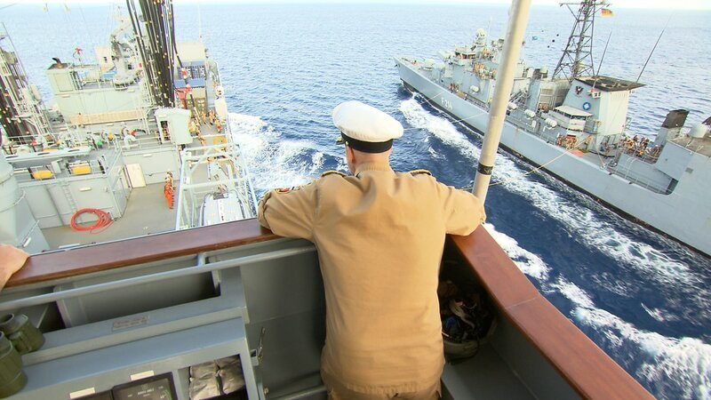 Der Kapitän des Schiffes lehnt an der Reling und beobachtet das Schiff. – Bild: Warner Bros. Discovery