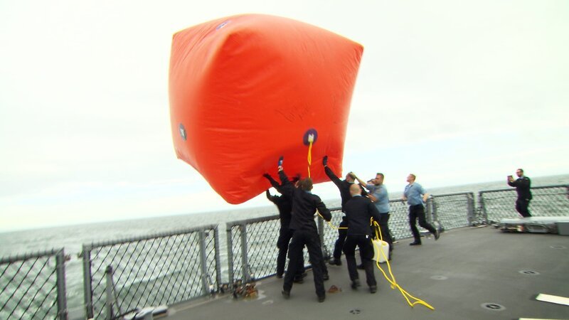 Auf dem deutschen Kriegsschiff „Nordrhein-Westfalen“ bereitet die Besatzung einen drei mal drei Meter großen Pressluftballon vor. – Bild: Warner Bros. Discovery