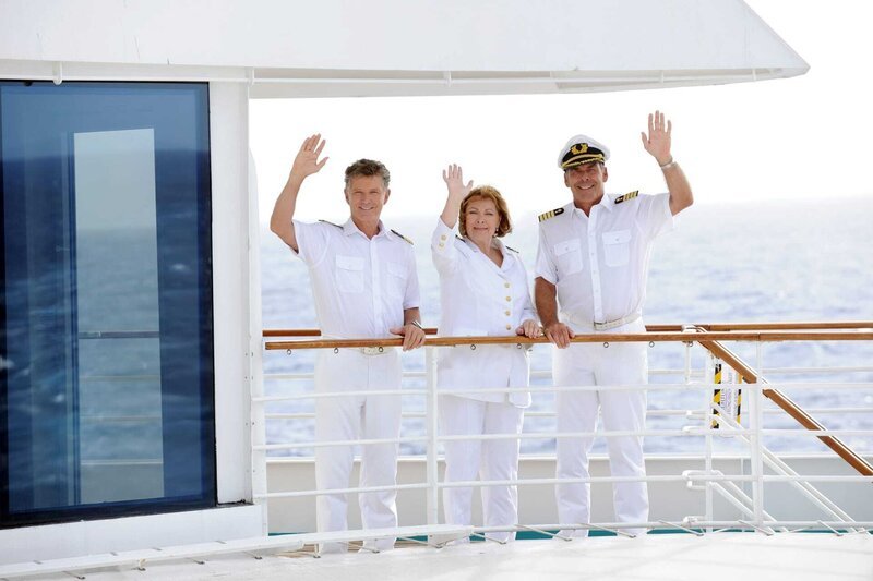 Dr. Sander (Nick Wilder), Beatrice (Heide Keller) und Kapitän Burger (Sascha Hehn) stehen winkend an Deck der MS Amadea. – Bild: ZDF/​Dirk Bartling