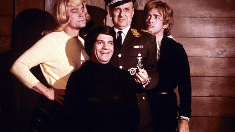 V.l.: Colonel Robert E. Hogan (Bob Crane), Corporal Louis LeBeau (Robert Clary), Colonel Wilhelm Klink (Werner Klemperer), Corporal Peter Newkirk (Richard Dawson) – Bild: TVNOW