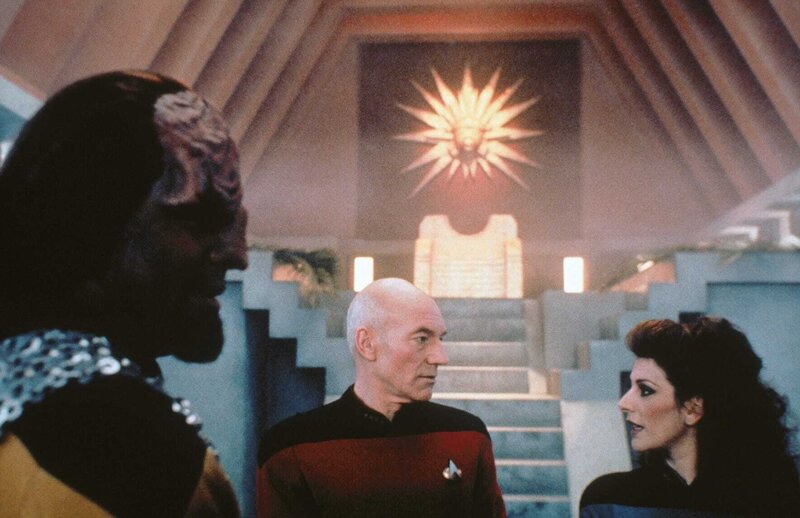 Captain Picard (Patrick Stewart, M.), Lt. Worf (Michael Dorn, l.) und Deanna Troi (Marina Sirtis, r.) befinden sich in einem Teil der Enterprise, der in einen Tempel verwandelt wurde. – Bild: NBC UNIVERSAL