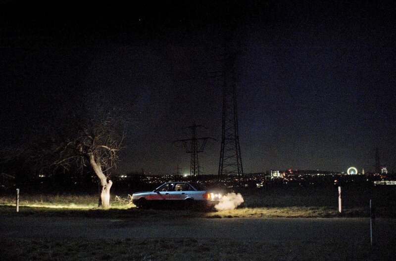 Der gegen den Baum gefahrene Audi 80 vor der nächtlichen Kulisse des Heimatortes der Freunde – Bild: SWR/Filmakademie Baden-Württemberg / Der gegen den Baum gefahrene Audi 80 vor der nächtlichen Kulisse des Heimatortes der Freunde Der gegen den Baum gefahrene Audi 80 vor der nächtlichen Kulisse des Heimatortes der Freunde – Bild: SWR/Filmakademie Baden-Württemberg / Der gegen den Baum gefahrene Audi 80 vor der nächtlichen Kulisse des Heimatortes der Freunde