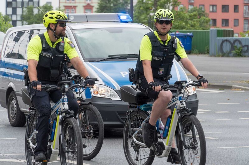 German policemen with yellow helmets and reflective jacket riding bikes – Bild: Shutterstock /​ Shutterstock /​ Copyright (c) 2020 Cineberg/​Shutterstock. No use without permission.