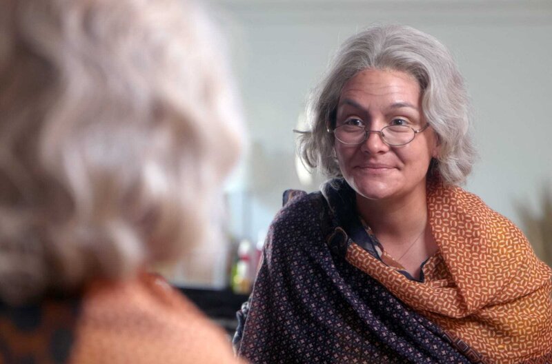 Ist die Rente noch sicher? – Bild: Anne Misselwitz /​ Estelle Vie-Hofmann wird von der Maskenbildnerin Diane Martin alt geschminkt. Sie schaut in den Spiegel.