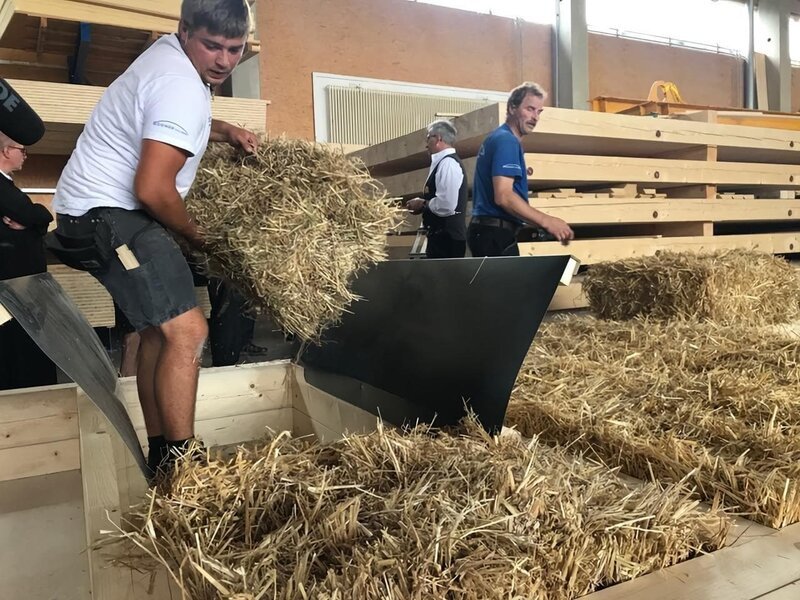 Eine Strohwand entsteht: Strohquader werden in ein Holzgefach eingepasst. – Bild: BR /​ BR