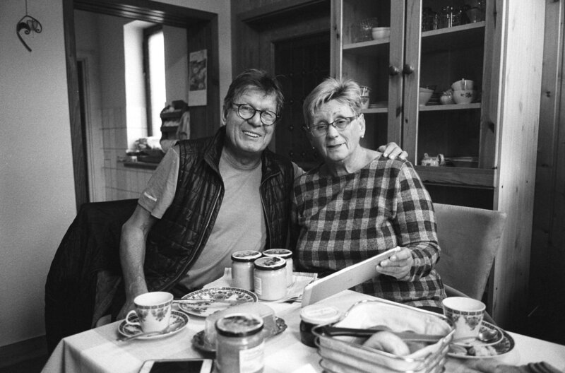 Anfang 1990, vor über dreißig Jahren, fuhr der Filmemacher Wolfgang Ettlich durch die DDR, ein Land im Umbruch. Er fuhr von Süden nach Norden, zur Ostsee und wieder zurück. Er begegnete Menschen, die ihn tief beeindruckten. Jetzt machte der Münchner sich wieder auf den Weg quer durch die „neuen Bundesländer“, fuhr erneut durch die Städte und Dörfer. Was wurde aus den Menschen von damals? – Karin Schütze mit Wolfgang Ettlich, Zschopau 2019. – Bild: rbb/​Hans Albrecht Lusznat