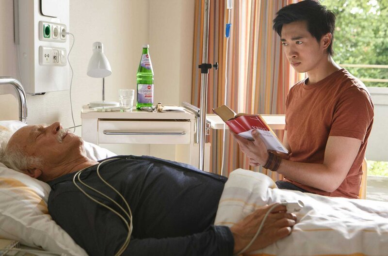 Nach seinem Herzinfarkt liegt Edwin (Tilo Prückner, l.) im Krankenhaus und langweilt sich tödlich. Doch dann erzählt ihm Hui Ko (Aaron Le, r.) von einem neuen Fall. – Bild: NDR/​ARD/​Kai Schulz
