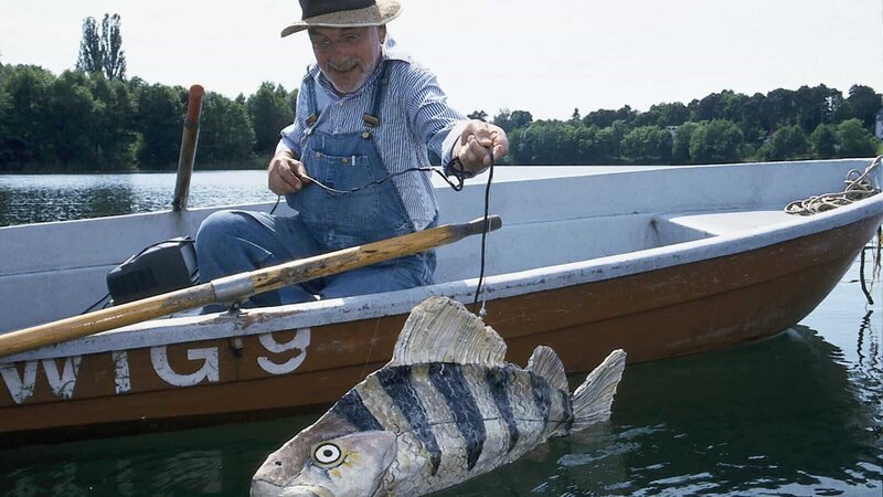 Peter (Peter Lustig) hat sich einen großen Fisch gebastelt. Im Inneren des Fisches steckt eine Kamera. Peter wird den Fisch schwimmen lassen, vielleicht erhält er so Fotos von dem Bärstädter See-Monster. – Bild: ZDF und Christiane Pausch.
