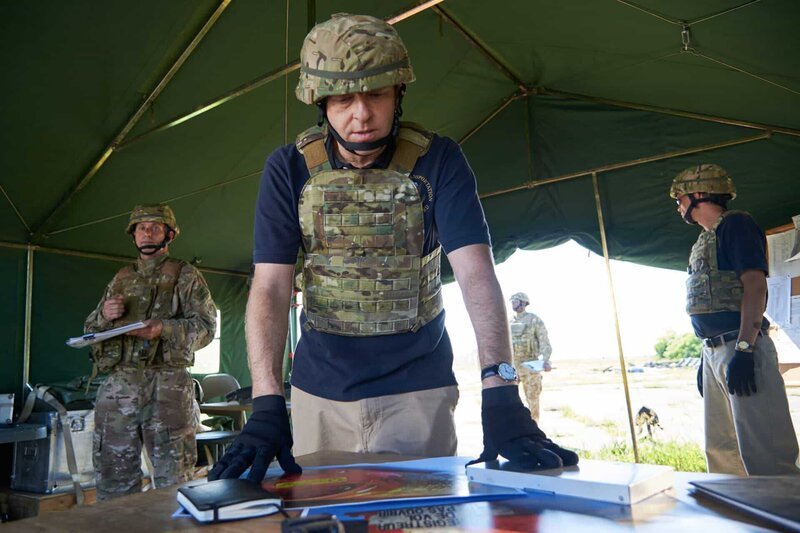 ONTARIO – RE-ENACTMENT – Investigator (played by Dmitry Chepovetsky) looks over photos from the crash in the crash site tent while military personnel (played by background performers) stand by.   – Bild: Cineflix /​ Steven Lungley