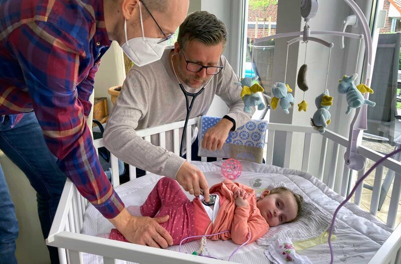 Christian Clermont (re.) und seine schwerkranke Tochter Ella, die vom Kinderpalliativarzt Dr. Merlin Deckers von den „Kleinen Riesen“ aus Kassel nun auch digital betreut wird. – Bild: HR/​Gabi Delingat