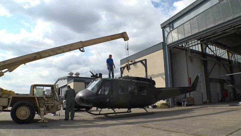 Michael Manousakis (l.) neben dem Militärhubschrauber Bell UH-1 Iroquois – Bild: Warner Bros. Discovery