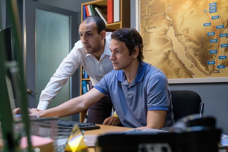 Der ägyptische Ermittler (gespielt von Nabeel El Khafif) und der russische Ermittler (gespielt von Robin Kasyanov) verwenden einen Computer, um den Absturz von MetroJet Flug 9268 zu untersuchen. – Bild: Darren Goldstein /​ Cineflix