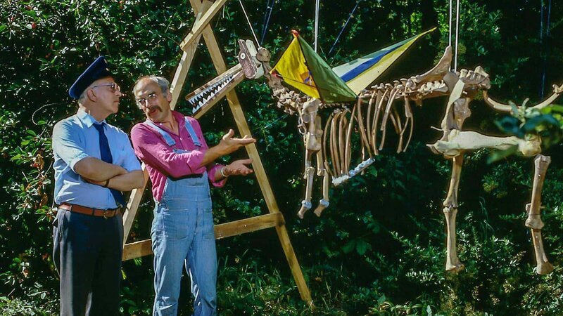 Peter (Peter Lustig, r.) hat einen riesigen Knochen im Garten gefunden. Ein so großer Knochen, denkt sich Peter, kann nur von einem großen Tier stammen – von einem Saurier! Er rekonstruiert das Skelett des Urwesens. – Bild: ZDF und studio tv.