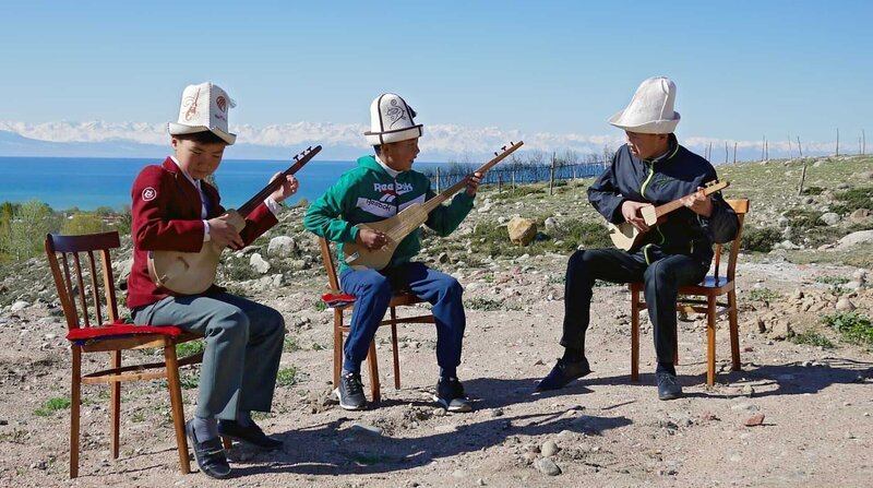 Ümöt Dolootov (mitte) ist 11 Jahre alt und spielt mit seinen Freunden die Komuz, eine dreisaitige Gitarre. – Bild: ZDF und NDR/TELLUX. Ümöt Dolootov (mitte) ist 11 Jahre alt und spielt mit seinen Freunden die Komuz, eine dreisaitige Gitarre. – Bild: ZDF und NDR/TELLUX.