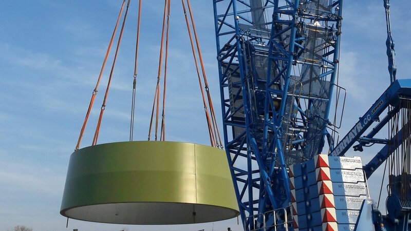 Ein Kran setzt das erste Turmsegment des Windrades auf das vorbereitete Fundament. – Bild: BILD