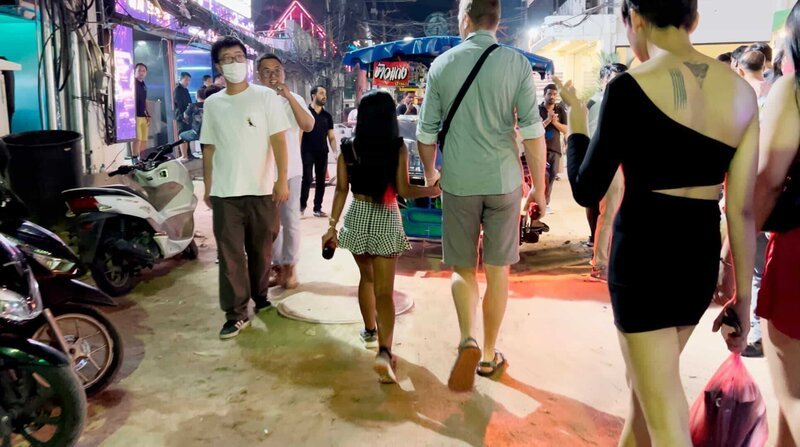 Mehrere Menschen gehen durch ein Rotlichtviertel im thailändischen Pattaya. – Bild: ZDF und NDR.