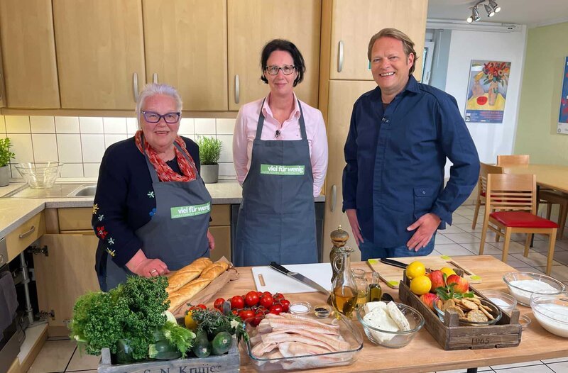 Die Eherenamtlerinnen Brigitte Scheuss (l.) und Heidi Zimmermann (M) kochen gemeinsam mit Björn Freitag gesunde Hausmannskost. – Bild: WDR/​solis TV/​Joshua Stolz