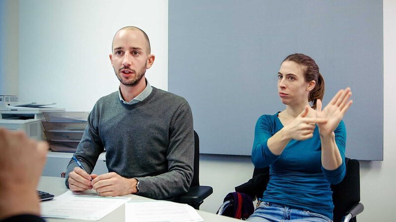 Gebärdedolmetscherin und Berater bei einem Beratungsgespräch. – Bild: ORF/​Navigator Film
