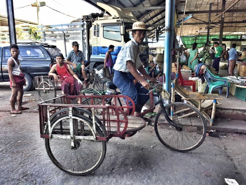 Ein Fahrradfahrer auf einem Markt in Yangon, Myanmar. – Bild: Bewegte Zeiten Filmproduktion GmbH/​BR/​Hanna Günther