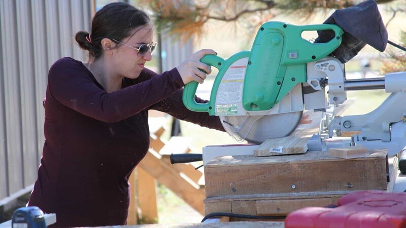 Lily is cutting a board with a miter saw for the Anibas build, in Colorado Springs, Colorado, as seen on Tiny House, Big Living. – Bild: 2017, Scripps Networks, LLC. All Rights Reserved.