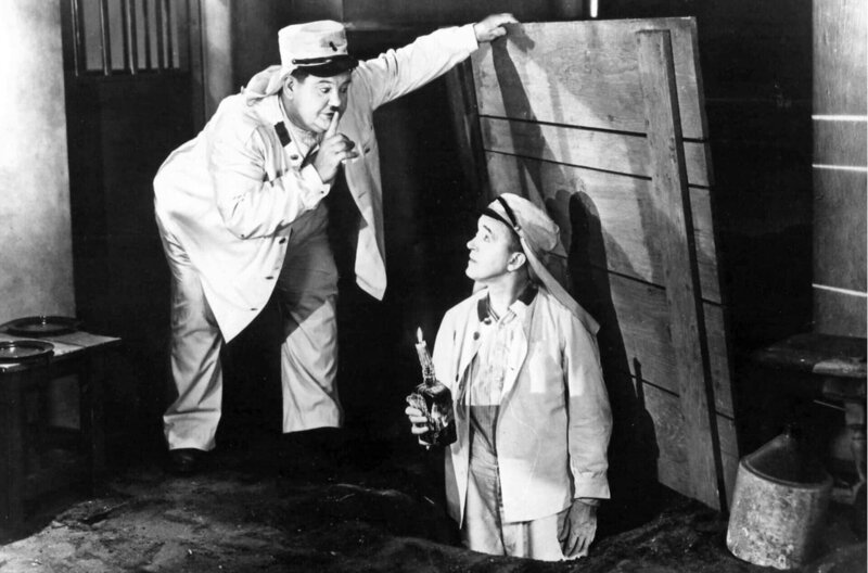 Ollie (Oliver Hardy, li.) entdeckt eine Fluchtmöglichkeit und türmt zusammen mit Stan (Stan Laurel, re.) aus der Gefängniszelle. – Bild: Club Laurel et Hardy /​ Ollie (Oliver Hardy, li.) entdeckt eine Fluchtmöglichkeit und türmt zusammen mit Stan (Stan Laurel, re.) aus der Gefängniszelle.