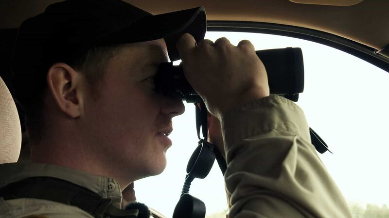 Officer Kimball looking through binoculars. – Bild: DMAX