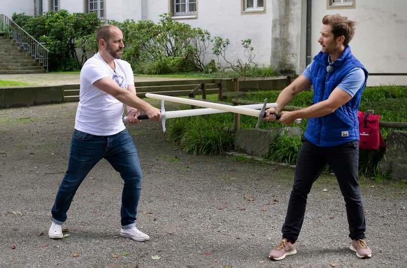 Im Hof des Deutschen Klingenmuseums lernt Daniel Aßmann (r) von Kurator Sixt Wetzler, was Schwertkampf mit Tanzen zu tun hat. – Bild: HR/​WDR/​Antje Baumgarten