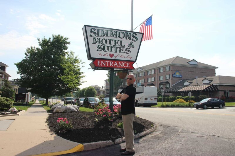 Host Anthony Melchiorri strikes a pose in front of the sign for the Simmons Motel in Hershey, Pennsylvania, as seen on Travel Channel’s Hotel Impossible. – Bild: 2015, The Travel Channel, L.L.C. All Rights Reserved.