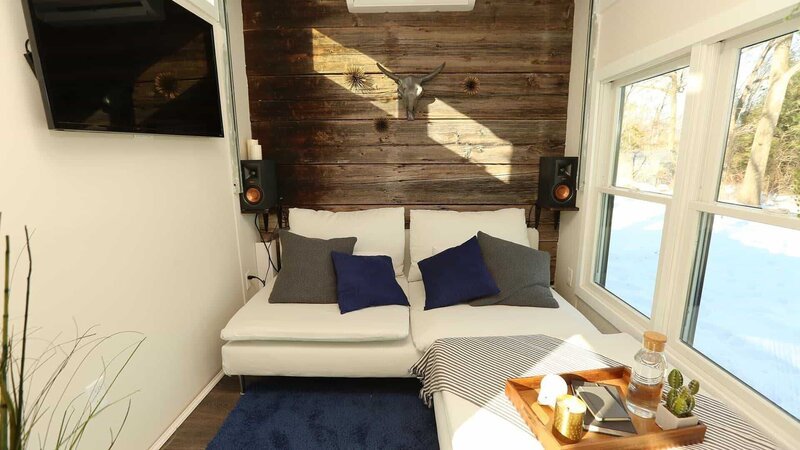 Sterling Folkestad’s tiny house features this sleek, modern living room with cozy white couches, a huge flat screen and a cozy bed that sits on a pulley system right above the living room and can be lowered down to be used by visiting friends and family here in Ipswich, Massachusetts, as seen on Tiny House, Big Living. – Bild: 2018, Scripps Networks, LLC. All Rights Reserved.