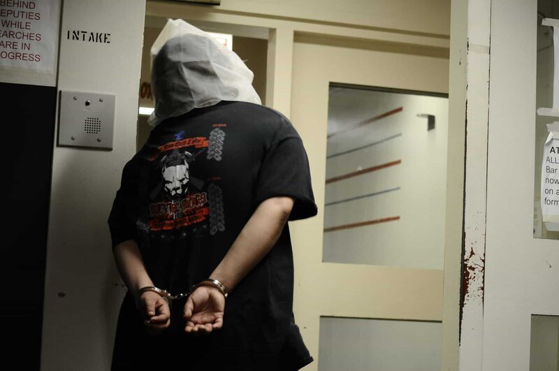 Sacramento, California: A new inmate in handcuffs with a spit mask to protect deputies from being split on while they are checked in. – Bild: National Geographic Channels