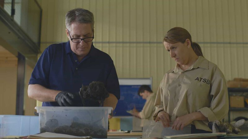 REENACTMENT – Beim Durchsuchen des Schlamms, der die Kabine des Sydney Seaplanes DHC-2 füllte, entdecken die Ermittler ein entscheidendes Beweisstück: eine Kamera, die einem der Passagiere an Bord gehörte. (Cineflix 2022) – Bild: Cineflix 2022 /​ Cineflix 2022