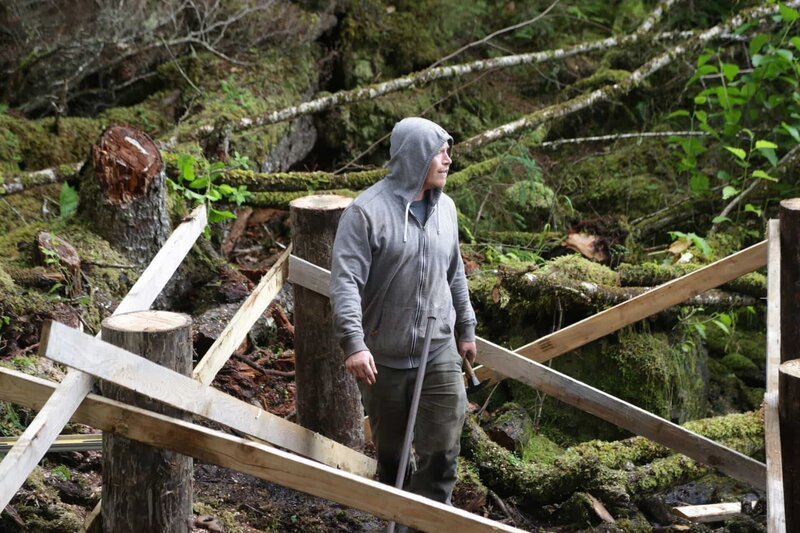 Troy Brockway bringt die Holzpfähle für seine neue Hütte an (National Geographic/​Gil Cano) – Bild: Wayne Moss /​ National Geographic /​ National Geographic/​Wayne Moss