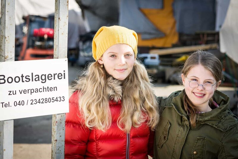 Stella (Zoë Malia Moon) und Pinja (Sina Michel) ziehen mit ihrer Mutter auf die alte Bootslagerei. – Bild: NDR/​Boris Laewen