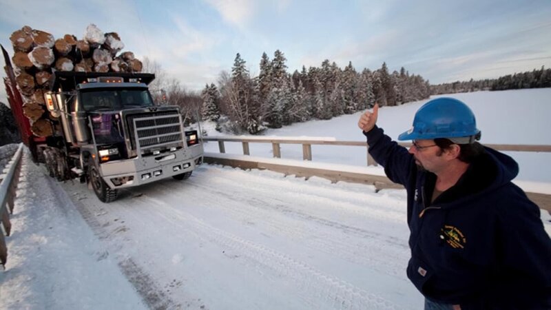Rudy Pelletier (in blue sweatshirt) and a logging truck with 275,000 pounds of timber driven by Lester Dube on a worksite at the Pelletier’s vast logging operation in Northern Maine. – Bild: David McLain/​Aurora /​ Discovery Channel /​ Discovery Communications LLC.