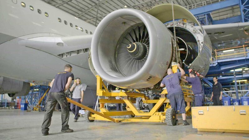 Um das Triebwerk auseinandernehmen und untersuchen zu können, wird die Turbine auf einen Hubwagen geladen. Etwa 70 Arbeiter hantieren gleichzeitig am A330–300. – Bild: N24 Doku