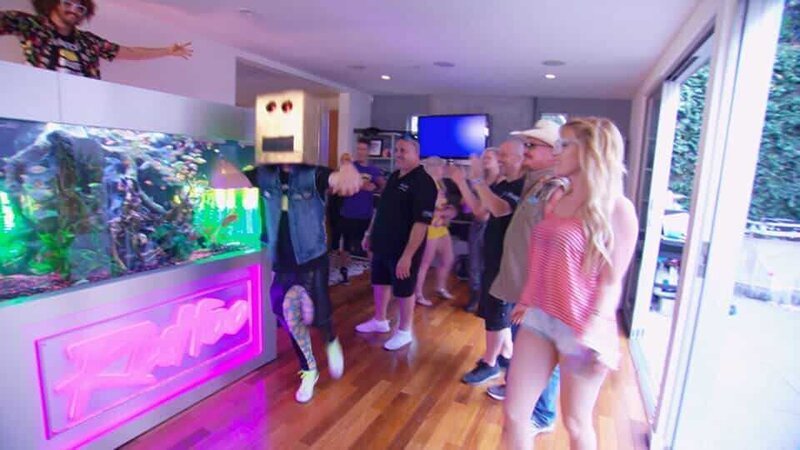 The LED lighting of the 1300 liter fish tank, in which a colorful crowd of underwater inhabitants cavort, flashes to the beat of the music that „Redfoo“ plays at the DJ station. – Bild: Warner Bros. Discovery