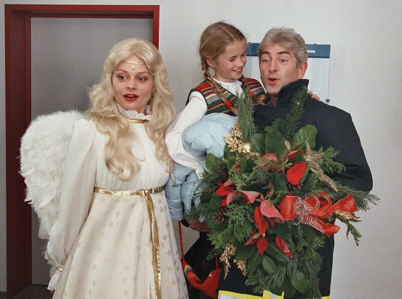 Marie Fiedler (Cornelia Gröschel) besucht gemeinsam mit ihrem Vati (Manfred Gorr) und dem Weihnachtsengel vom Weihnachtsmarkt (Susanna Simon) die Oma im Krankenhaus. – Bild: MDR