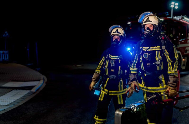 Zwei Bochumer Feuerwehrleute in voller Schutzausrüstung auf ihrem Weg zu einem nächtlichen Einsatz. – Bild: WDR/​Sebastian Drolshagen