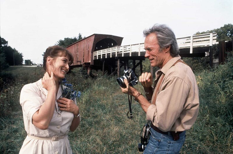 An der Roseman Bridge schenkt der Fotograf Robert (Clint Eastwood) Francesca (Meryl Streep) einen Blumenstrauß. – Bild: Warner Bros. /​ © Warner Bros.