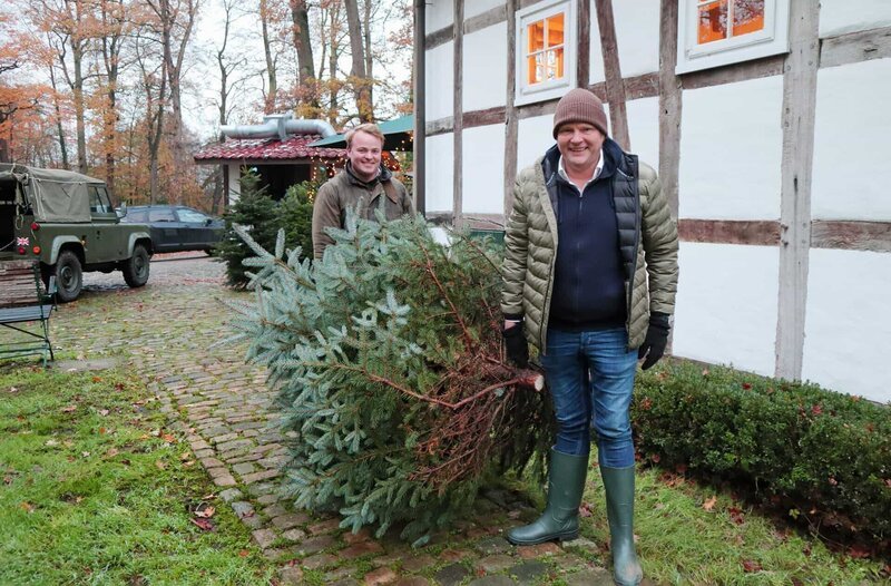 Björn Freitag (r) und Thedel Haver Rassfeld, Sohn des Hofes in Gütersloh, bringen den selbst geschlagenen Tannenbaum ins Haus. – Bild: WDR/​Andrea Ahmadi