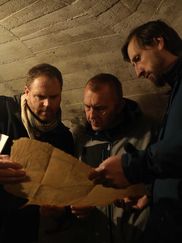 Sebastian Terenada () und Oliver Kruger (r.) zeigen Josh Gates (l.) eine Karte des Nazitunnels. – Bild: Adam Kostylo /​ Ping Pong Productions /​ Photobank /​ 37781_ep710_016 /​ Discovery Communications, LLC
