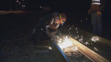 Arbeiter arbeiten an den Schienen. – Bild: Warner Bros. Discovery