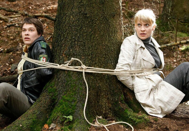 Sophie Haas (Caroline Peters, r.) und Bärbel Schmied (Meike Droste, l.) sind im Wald gekidnappt und an einen Baum gefesselt worden. – Bild: ARD